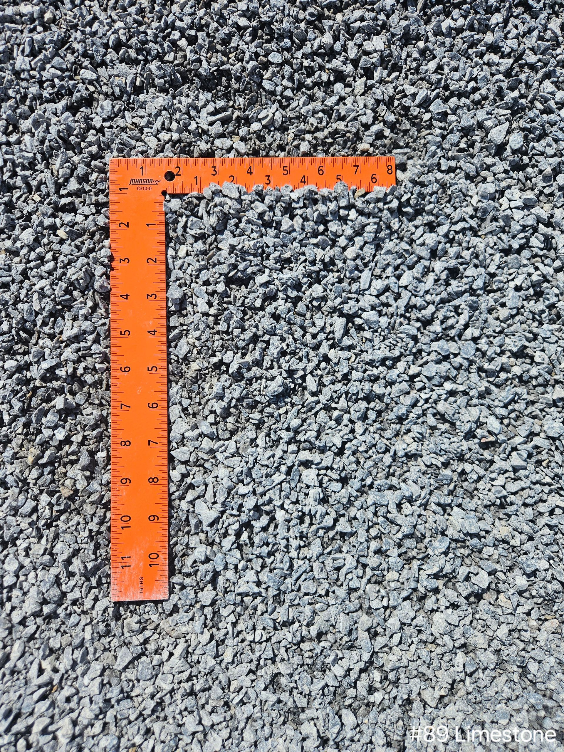 Orange ruler on a bed of gray gravel.