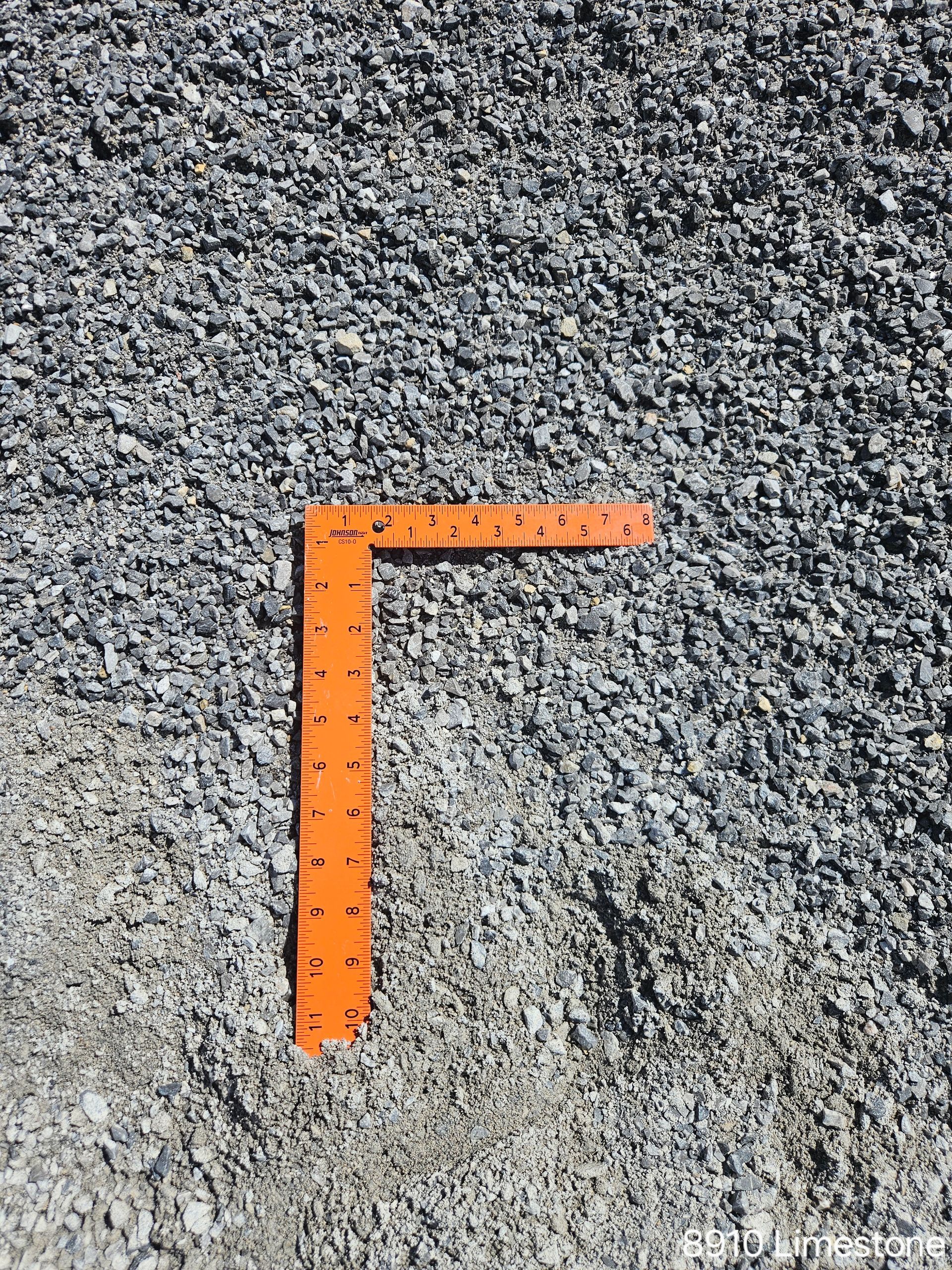Orange right angle tool on a bed of gray gravel.