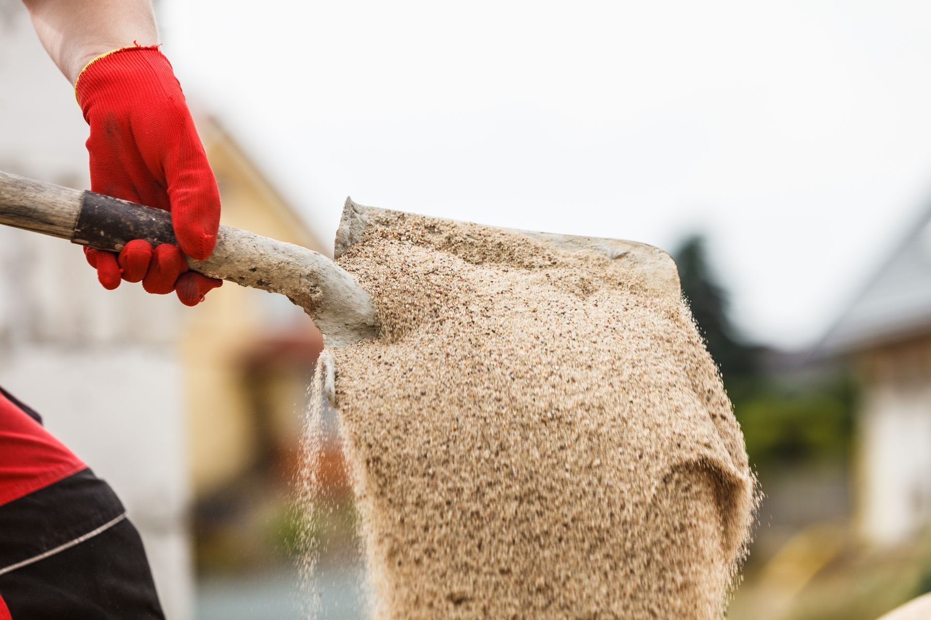 Close-up of a worker using a shovel with sand on a construction site, from a local sand supplier Close-up of a worker using a shovel with sand on a construction site, from a local sand supplier