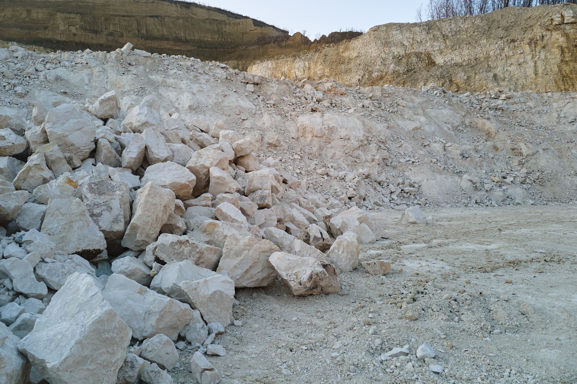 Large pile of limestone rocks in a quarry with exposed stone layers in the background. Large pile of limestone rocks in a quarry with exposed stone layers in the background.