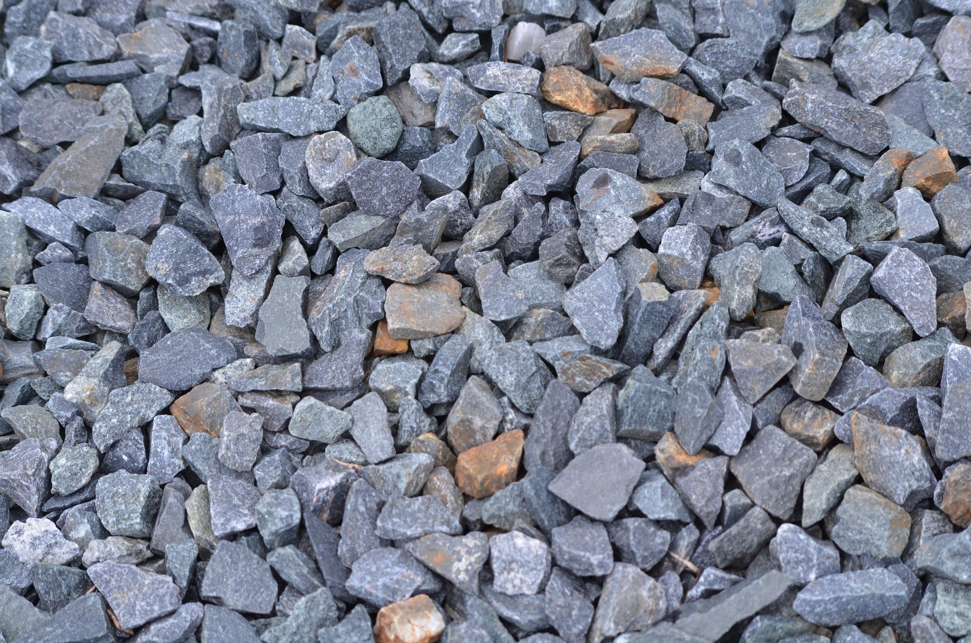 Close-up of angular gray and rust-colored crushed stone for driveways and paths.