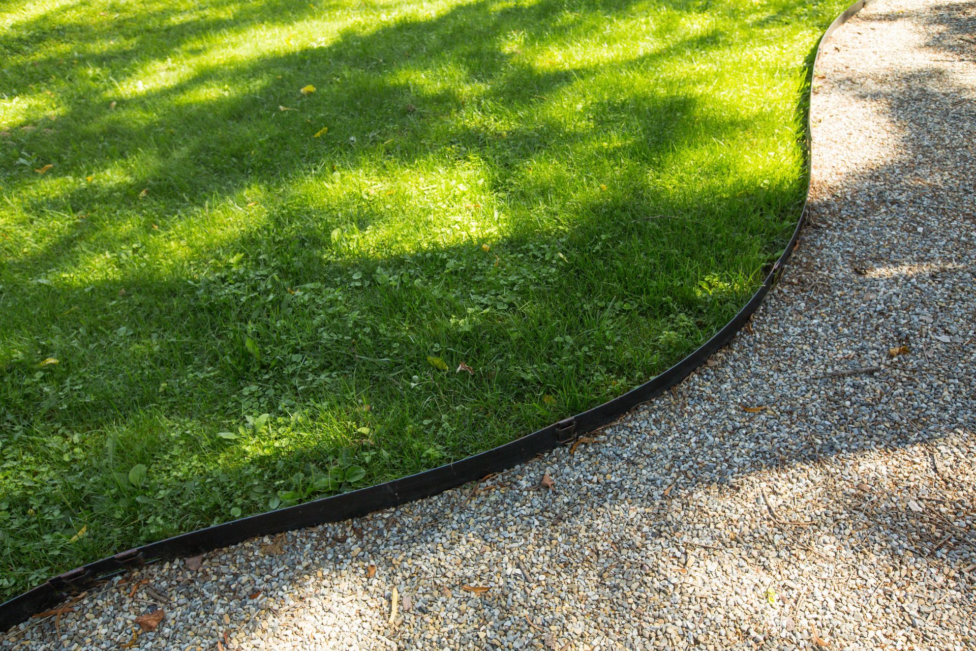 A lawn with a gravel path going through it and a black edging.