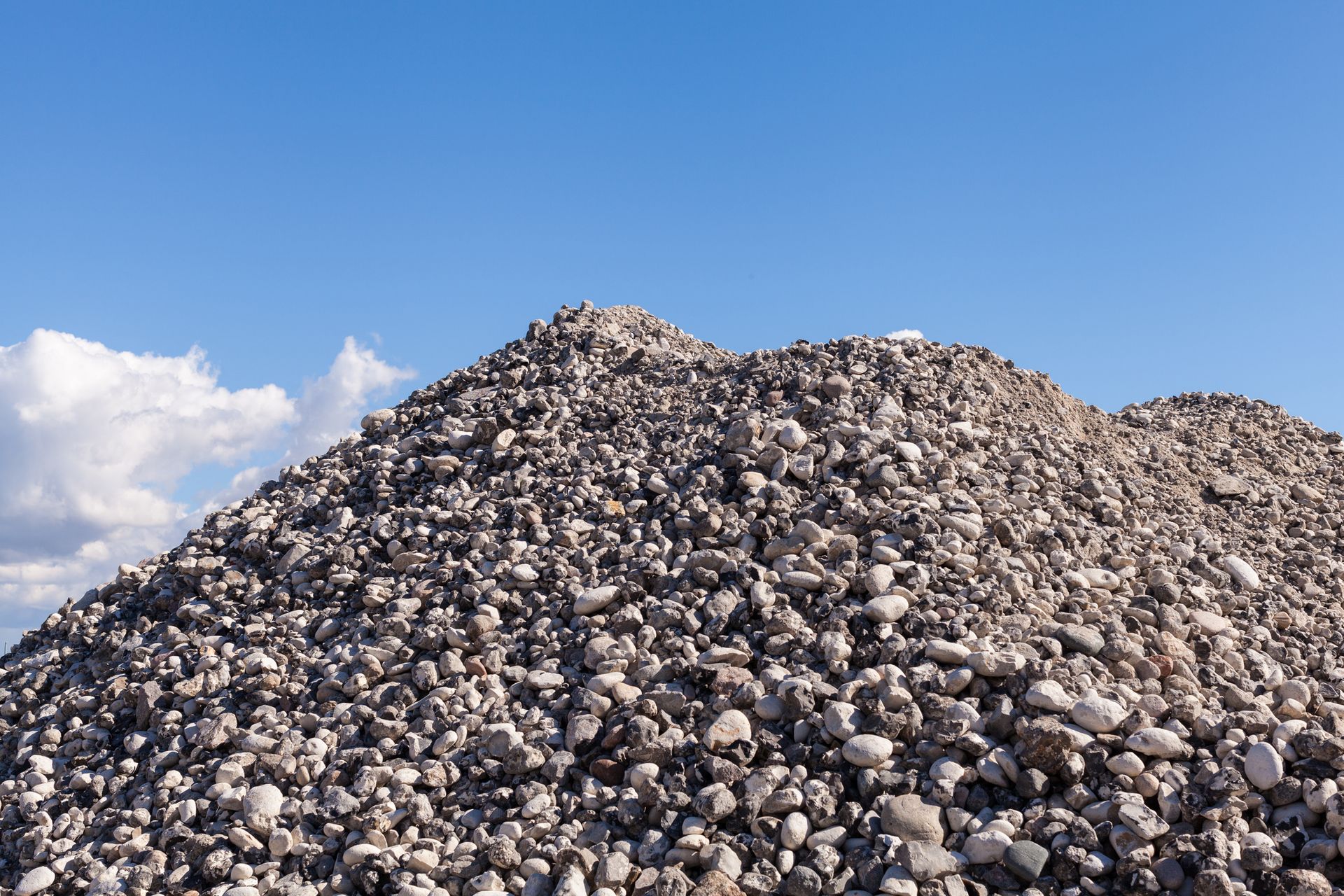 A pile of rocks against a blue sky with clouds