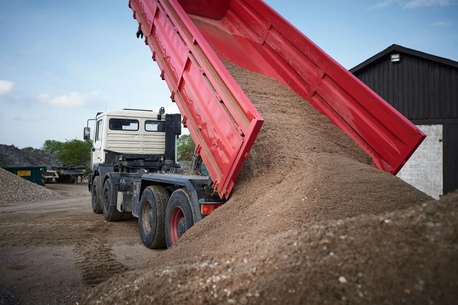 A construction truck dumps a pile of fine earth on the ground. A construction truck dumps a pile of fine earth on the ground.