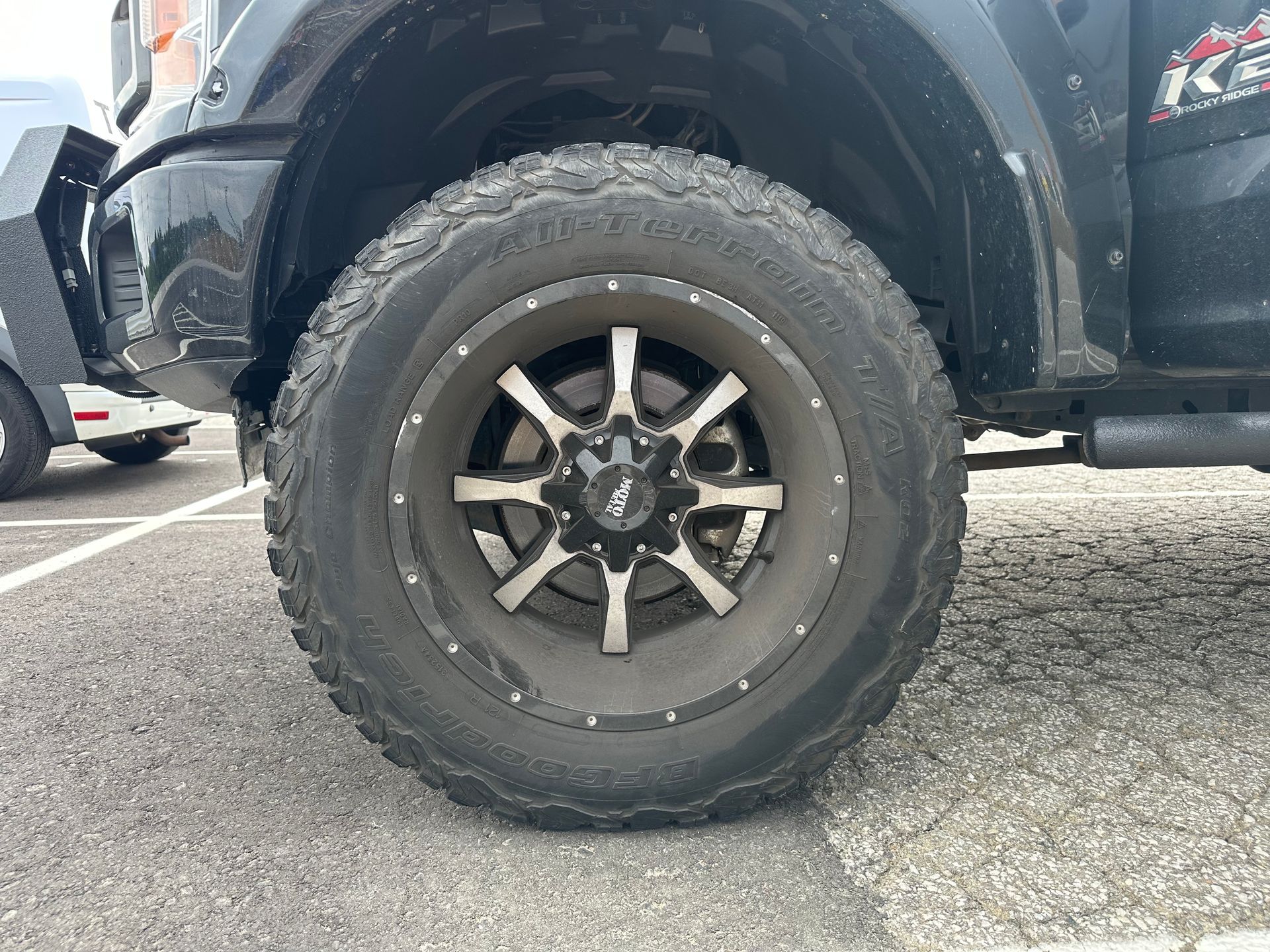 A close up of a tire on a truck in a parking lot.