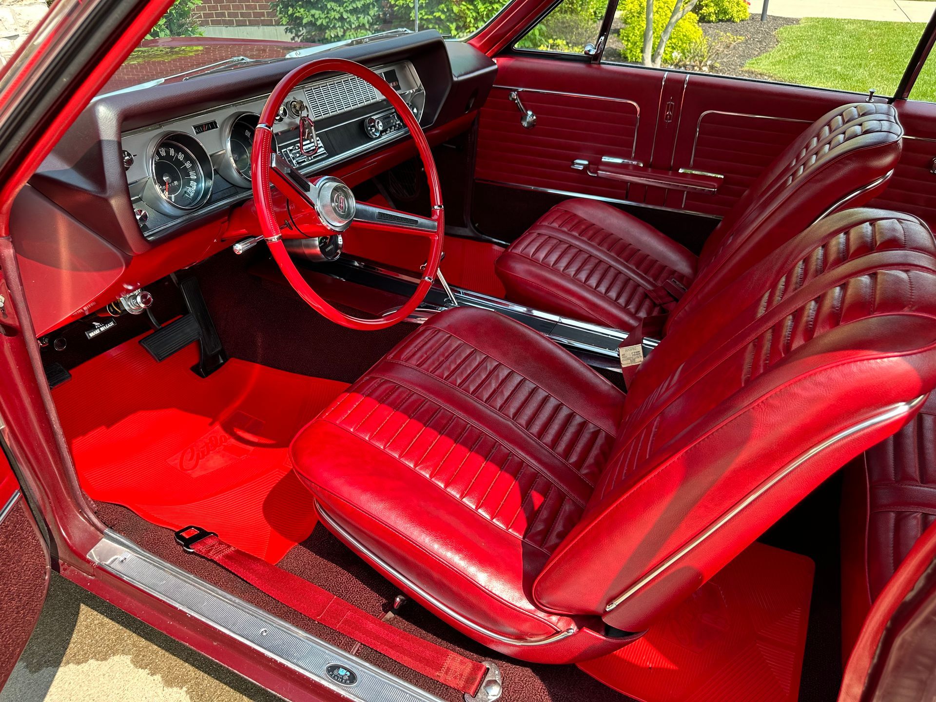 Blue Lamborghini interior: black suede seats and steering wheel, white racing stripes, metal pedals, and a center console.