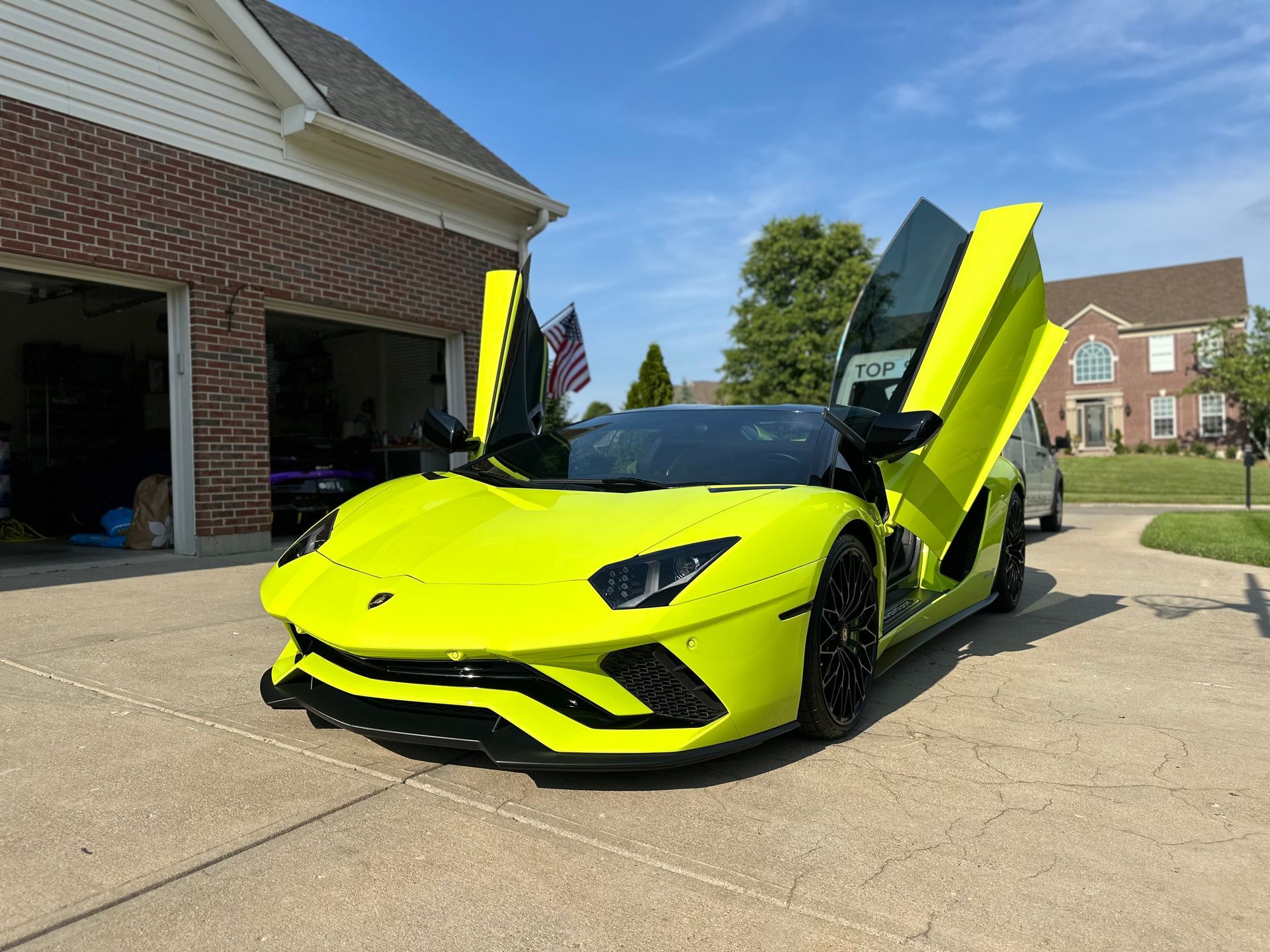 Bright yellow Lamborghini with doors up in front of a house.