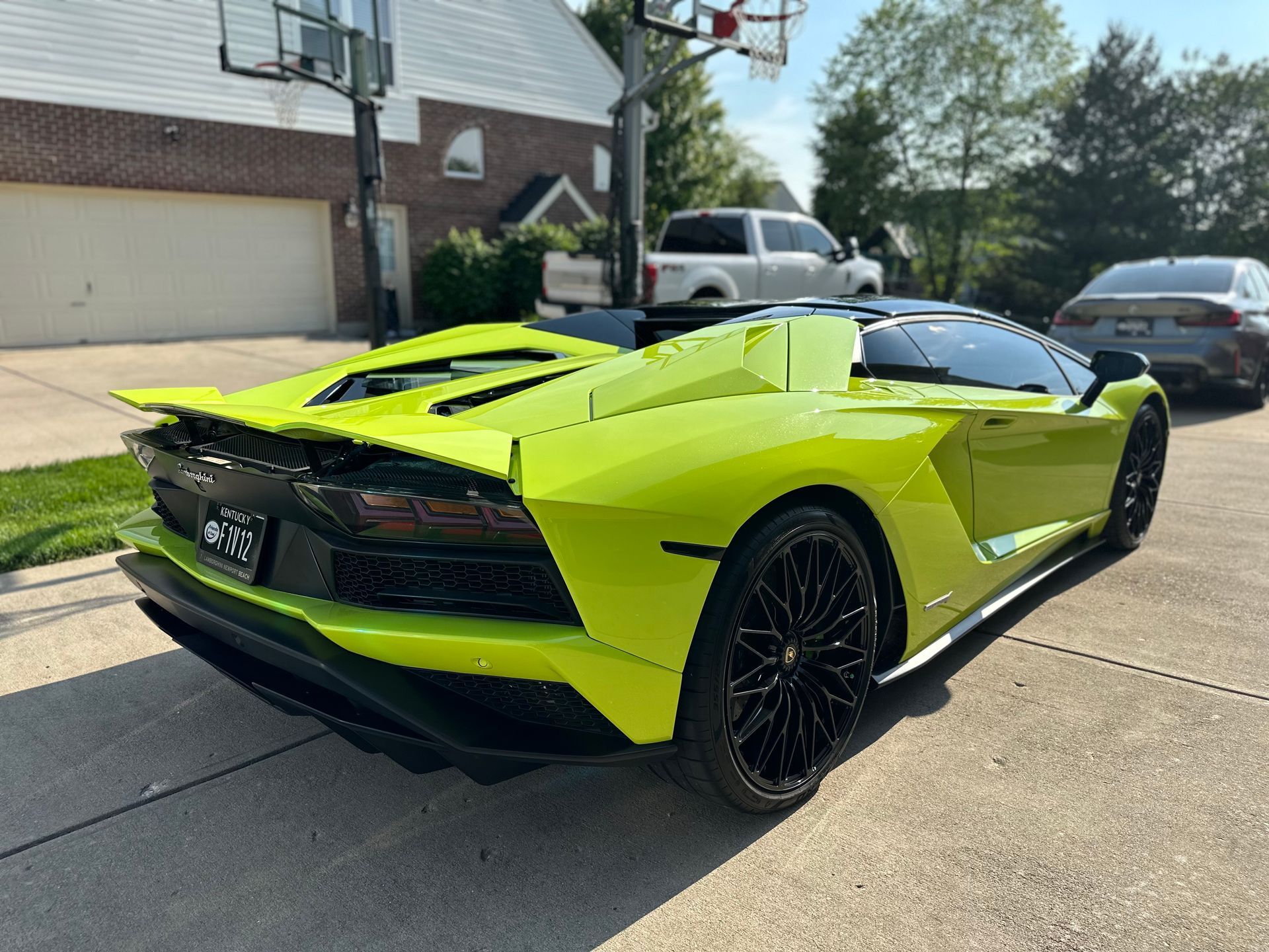 Lime green Lamborghini parked in a driveway, black wheels, against a residential backdrop.