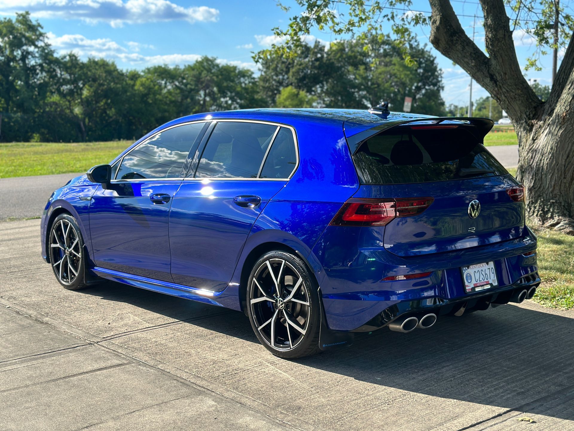 Blue Volkswagen Golf R hatchback with black wheels parked on a sunny day.