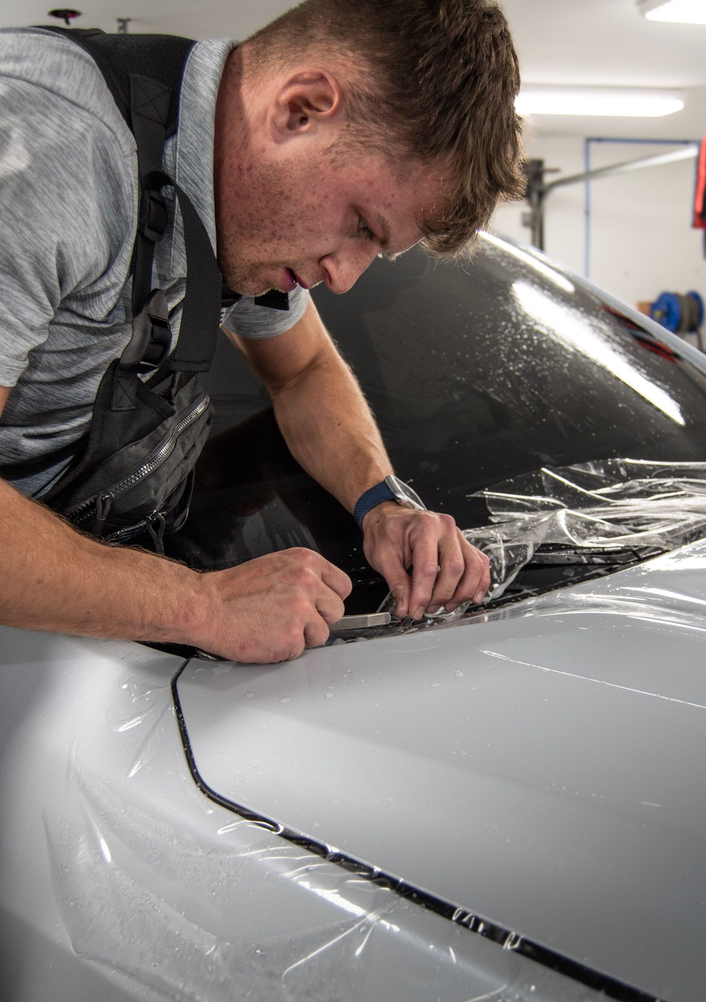 A person is cleaning a blue car with an orange towel
