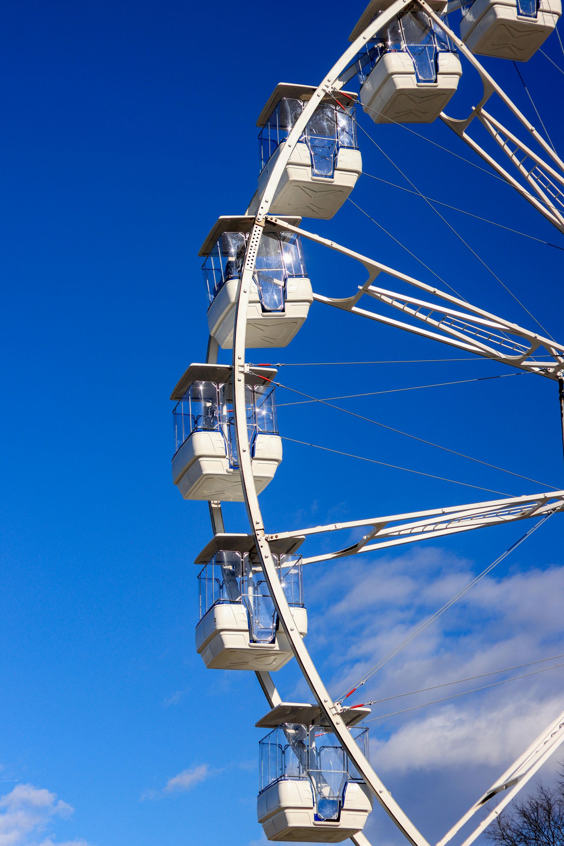 Ferris wheel with white cabins against a bright blue sky.