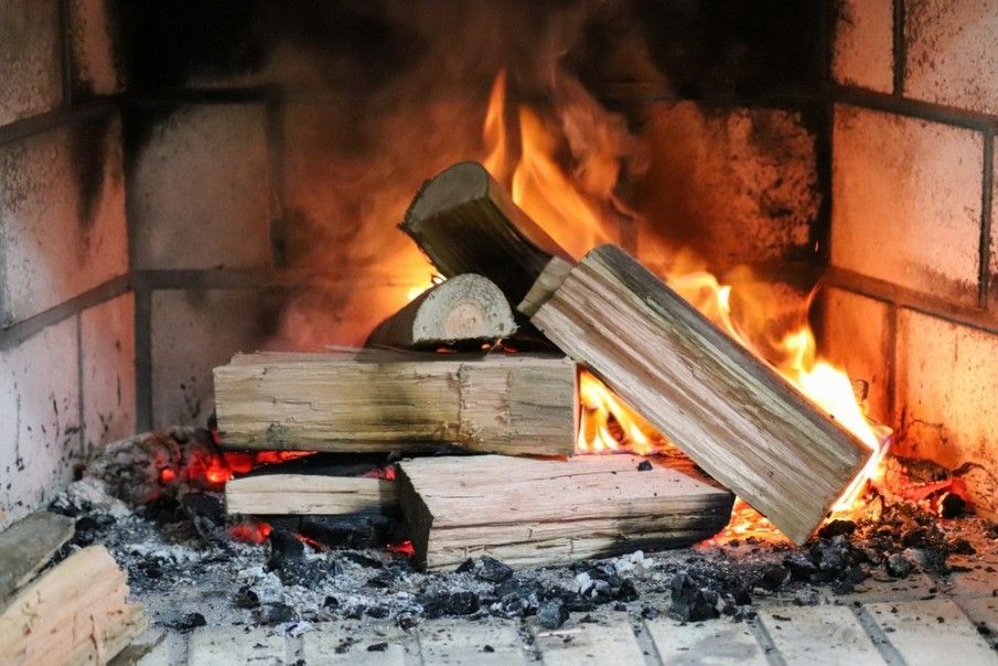 A Pile of Logs is Sitting in a Fireplace With Flames Coming Out of It — Ryno's Plumbing Group in Lakewood, NSW