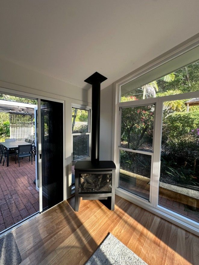 A Living Room With a Fireplace and Lots of Windows — Ryno's Plumbing Group in Forster, NSW