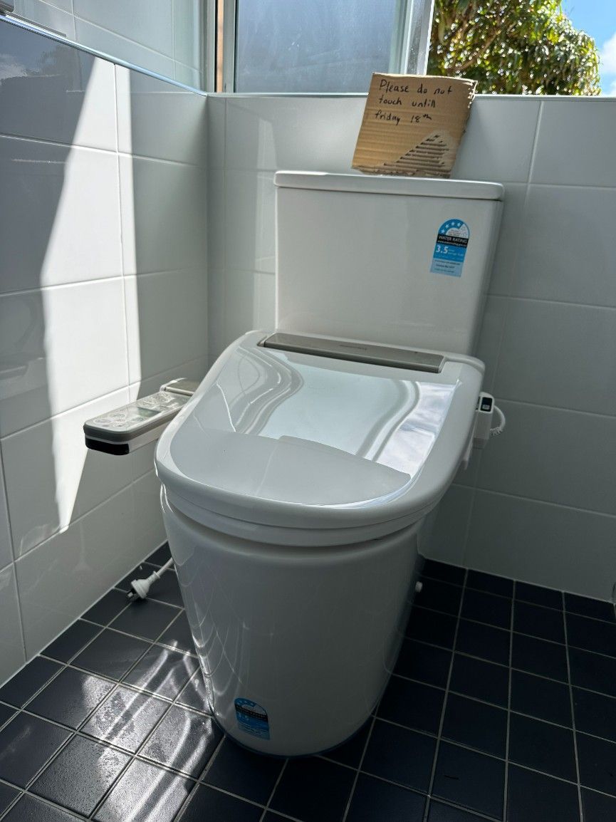 A White Toilet is Sitting in a Bathroom Next to a Window — Ryno's Plumbing Group in Lakewood, NSW