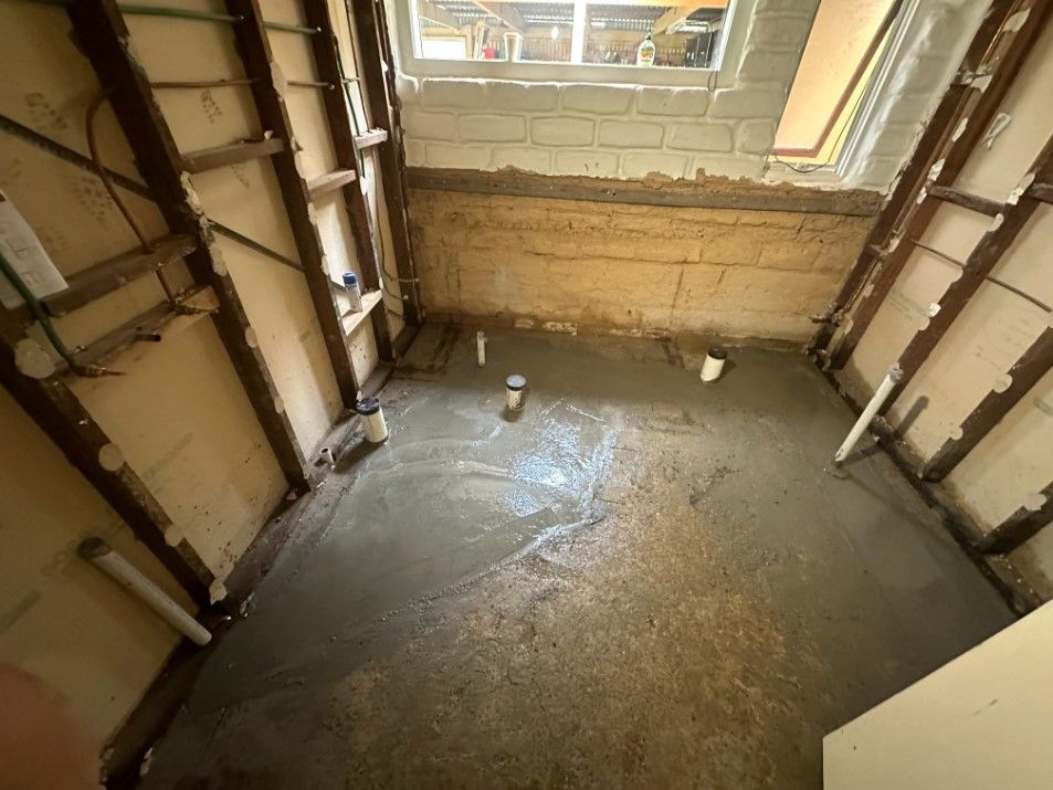 A Bathroom Under Construction With a Concrete Floor and a Window — Ryno's Plumbing Group in Lakewood, NSW