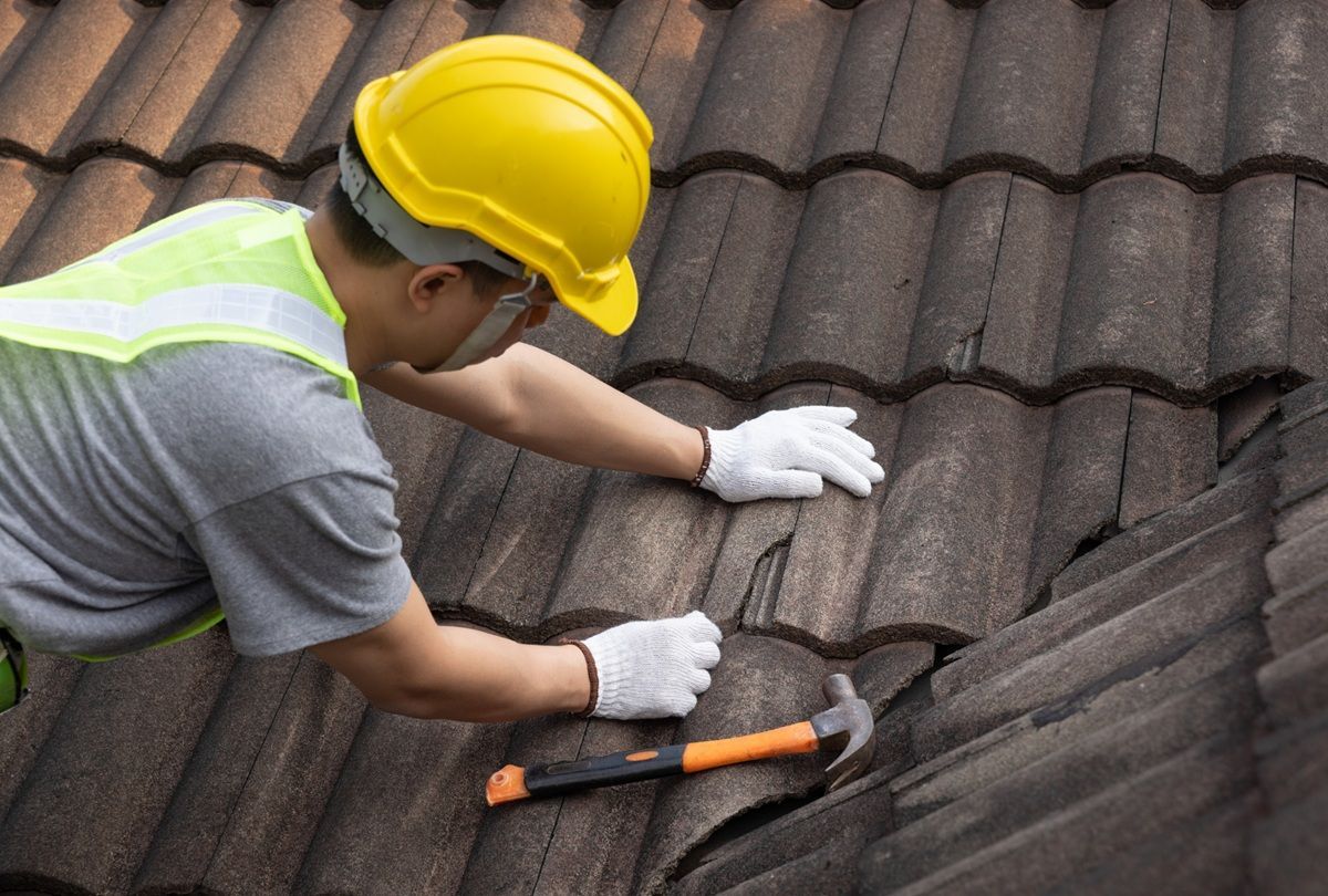 Roofing technician repairing damaged shingles on an Atwater home