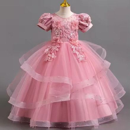 A pink dress with short sleeves and ruffles is on a mannequin.