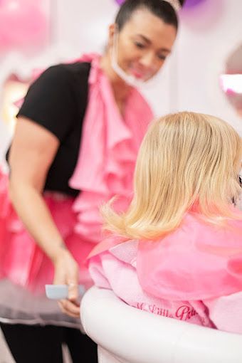 A little girl is getting her hair cut at a hair salon.
