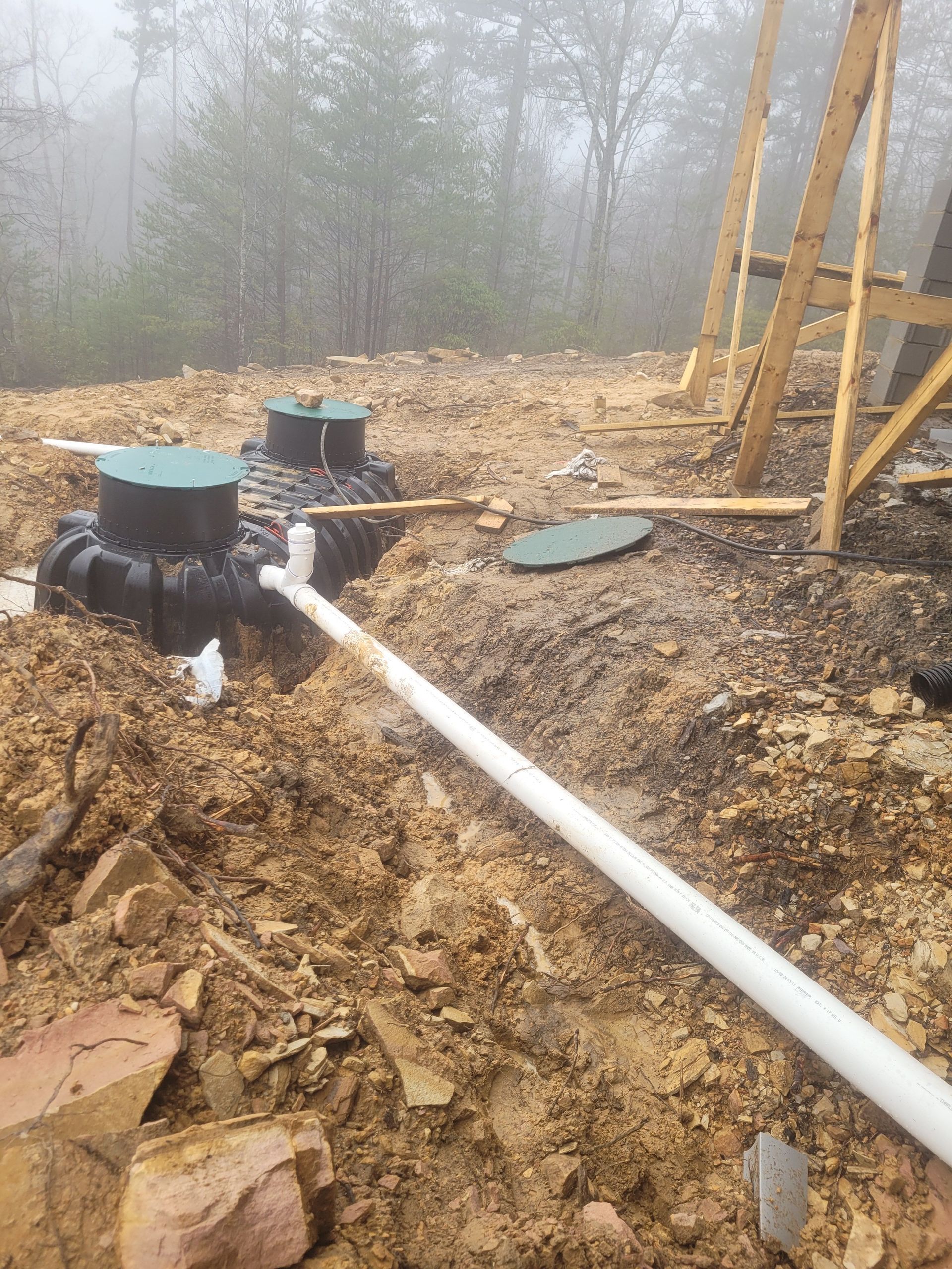 Construction site with septic tanks, white pipe, and exposed earth.