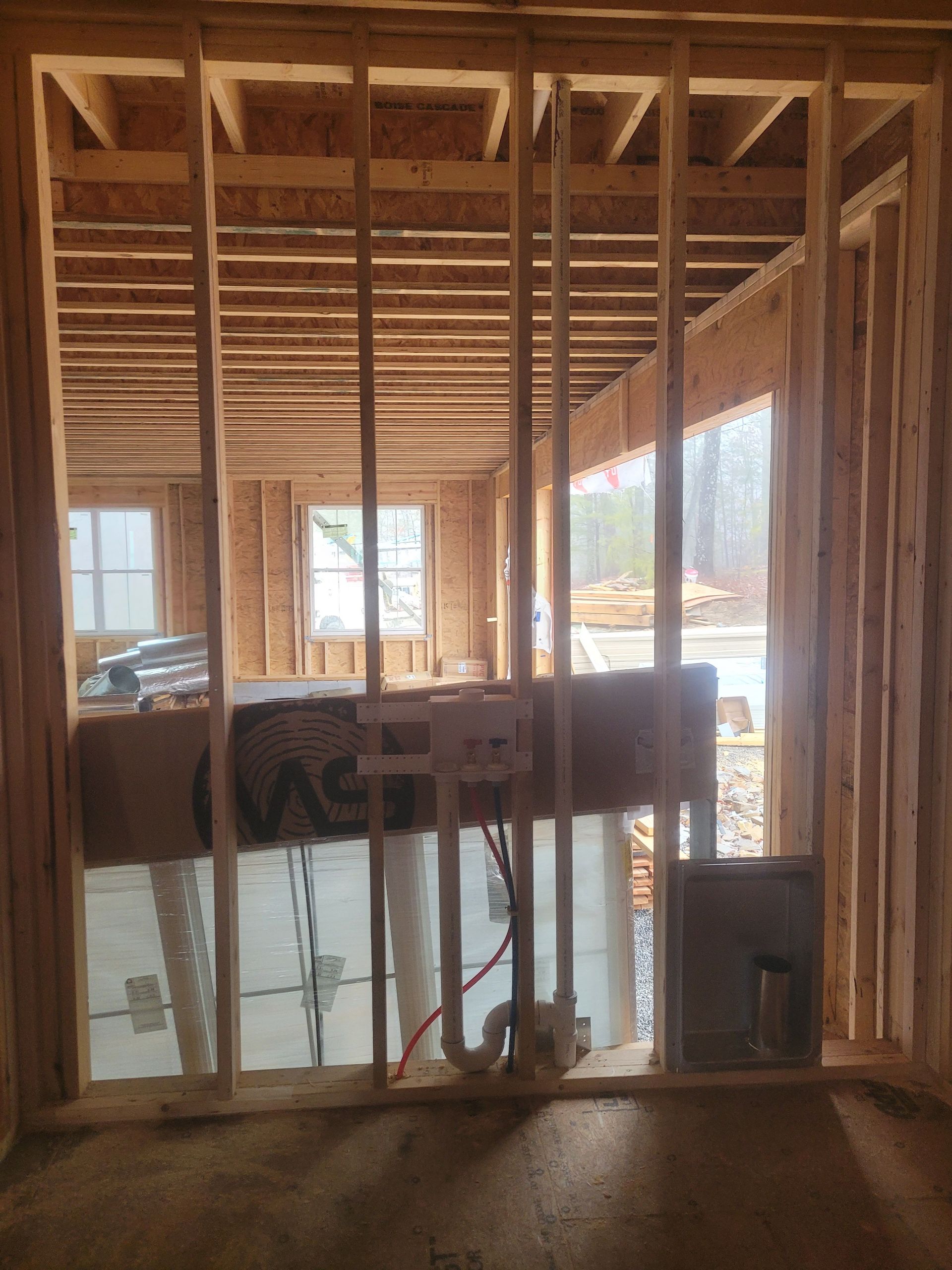 Unfinished bathroom framing with plumbing and electrical box. Interior view of a new construction site.