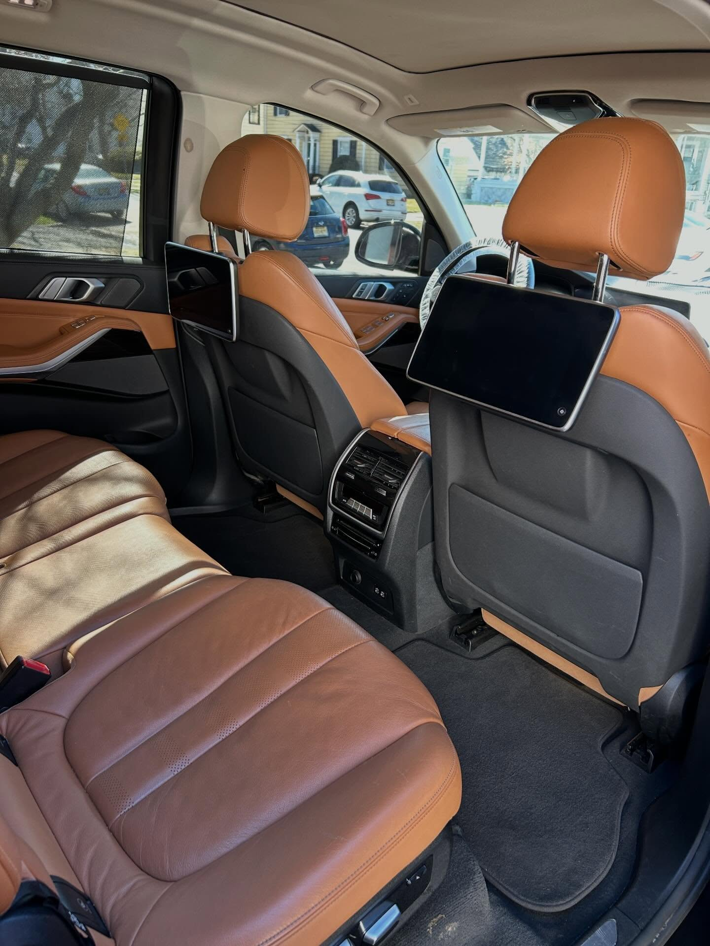 Car interior with brown leather seats, rear entertainment screens, and a sunroof.