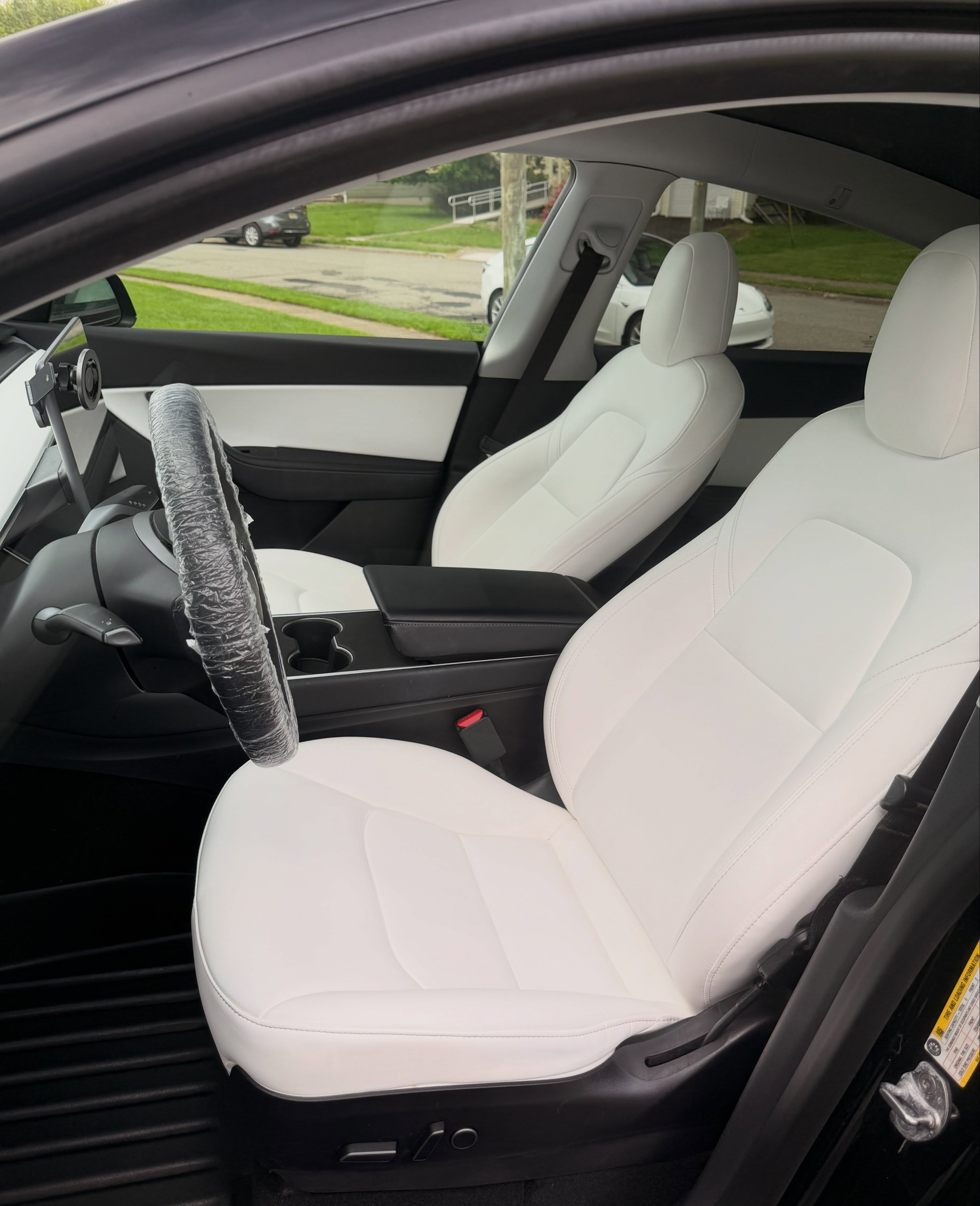 White car interior with black dashboard and seats, viewed through the open driver-side door
