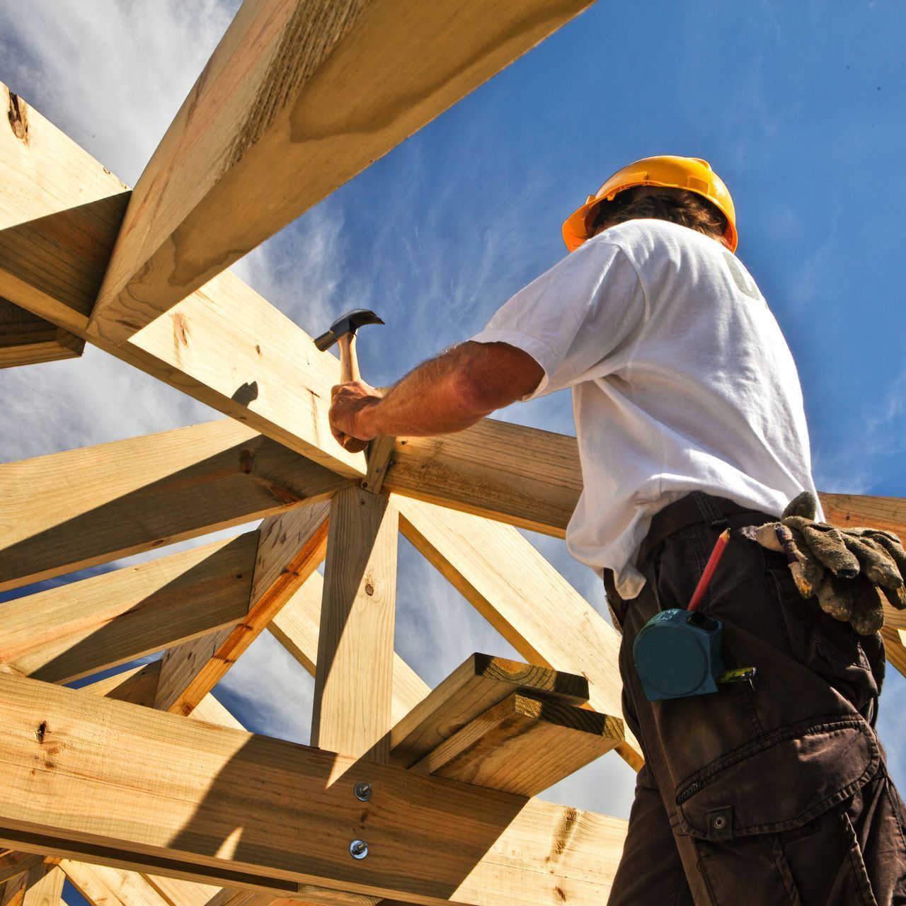 Un homme portant un casque de chantier travaille sur une structure en bois