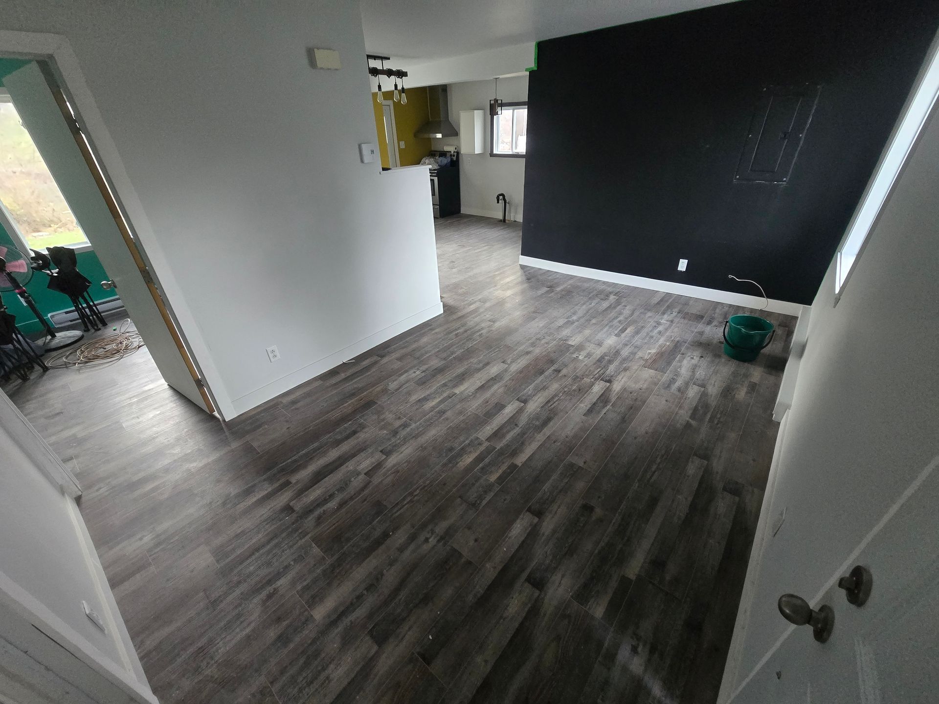 Un salon avec parquet et un mur noir.