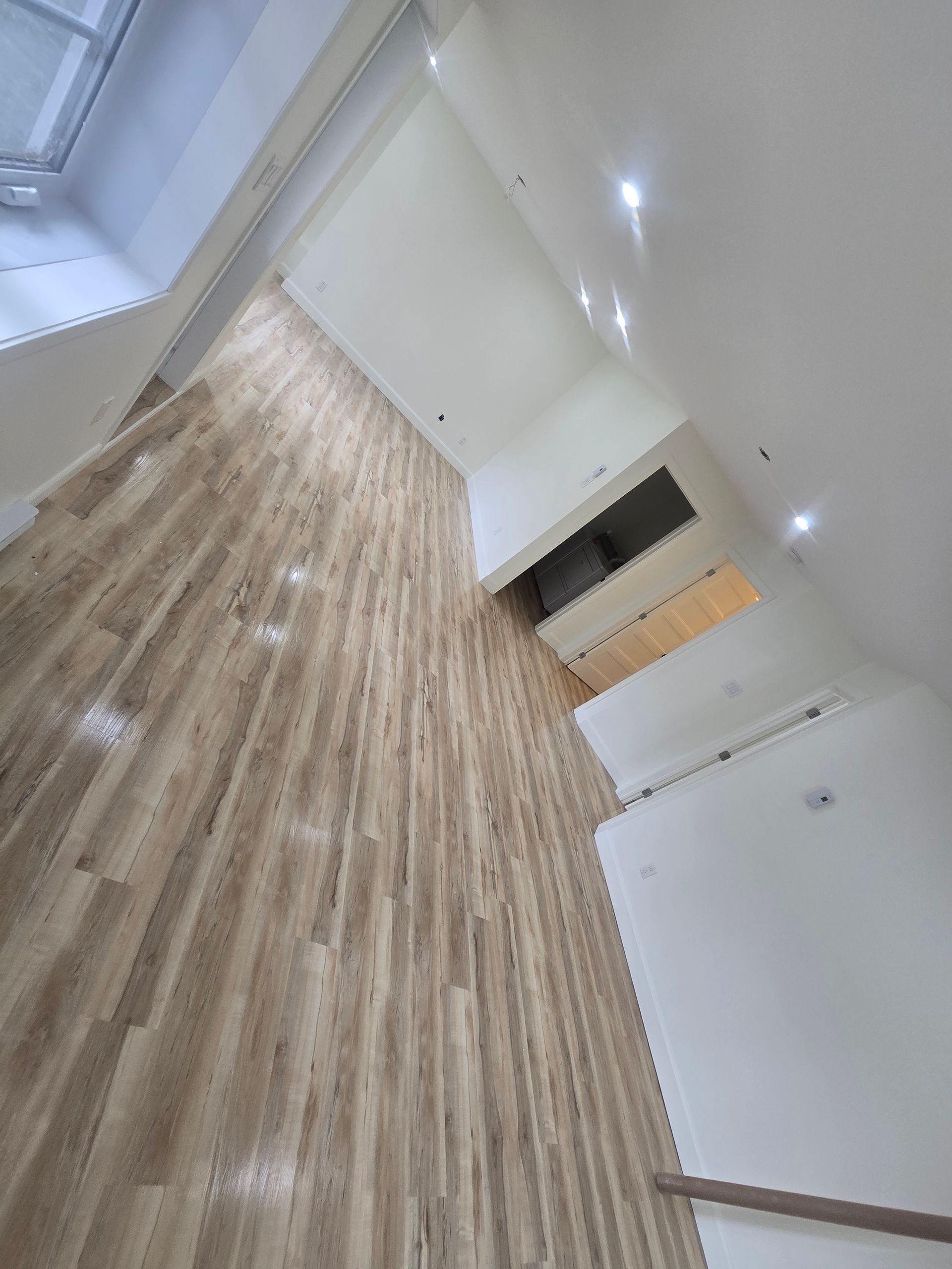 Une pièce avec un plancher en bois et des murs blancs.