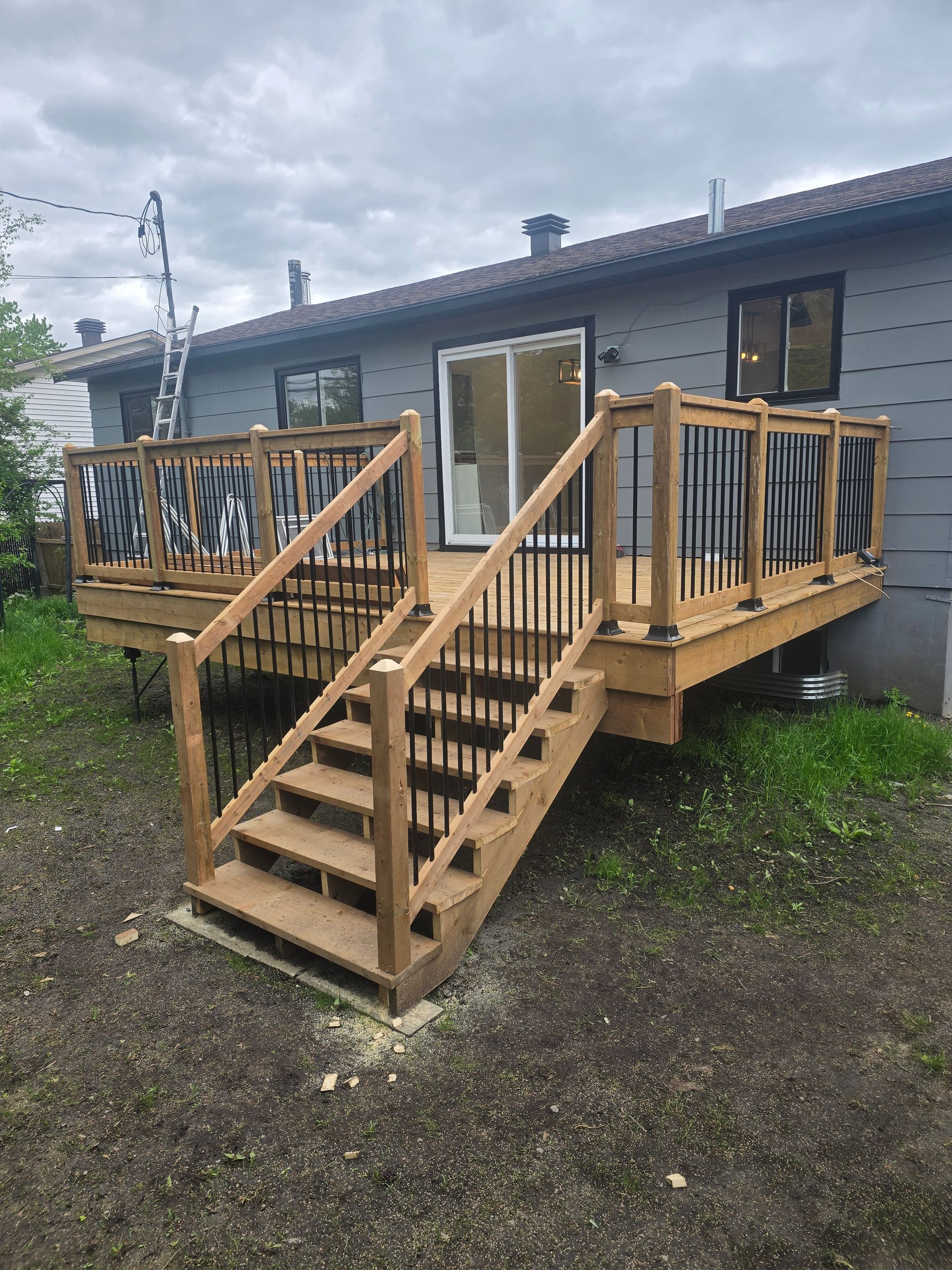 Une terrasse en bois avec des escaliers qui y mènent se trouve devant une maison.