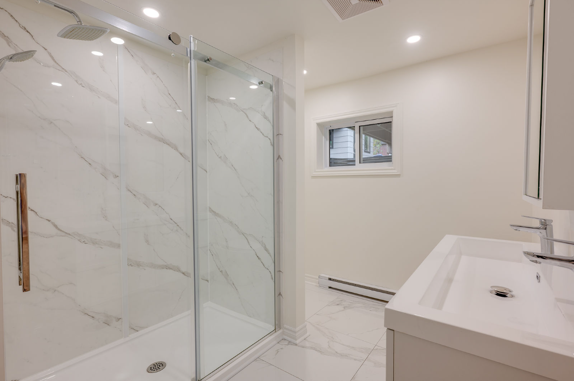 Une salle de bain avec douche à l'italienne, lavabo et miroir.