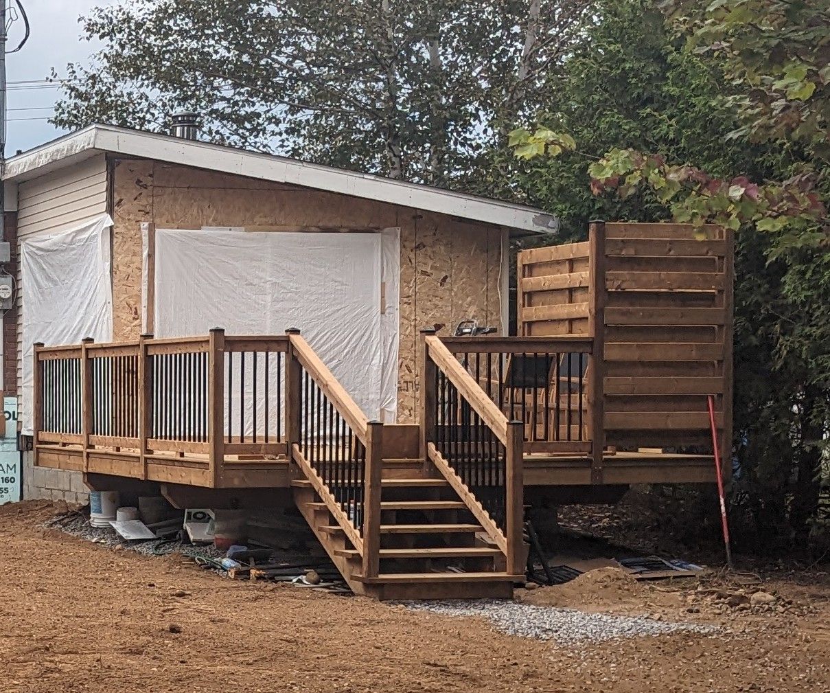 Une petite maison avec une terrasse en bois et des escaliers.