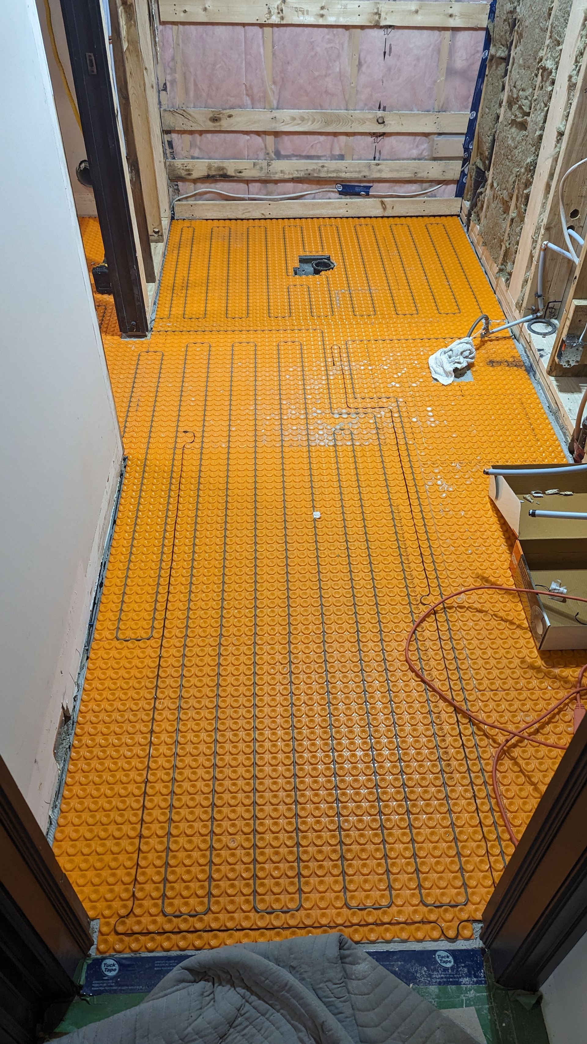 Une salle de bain en construction avec un tapis jaune sur le sol.