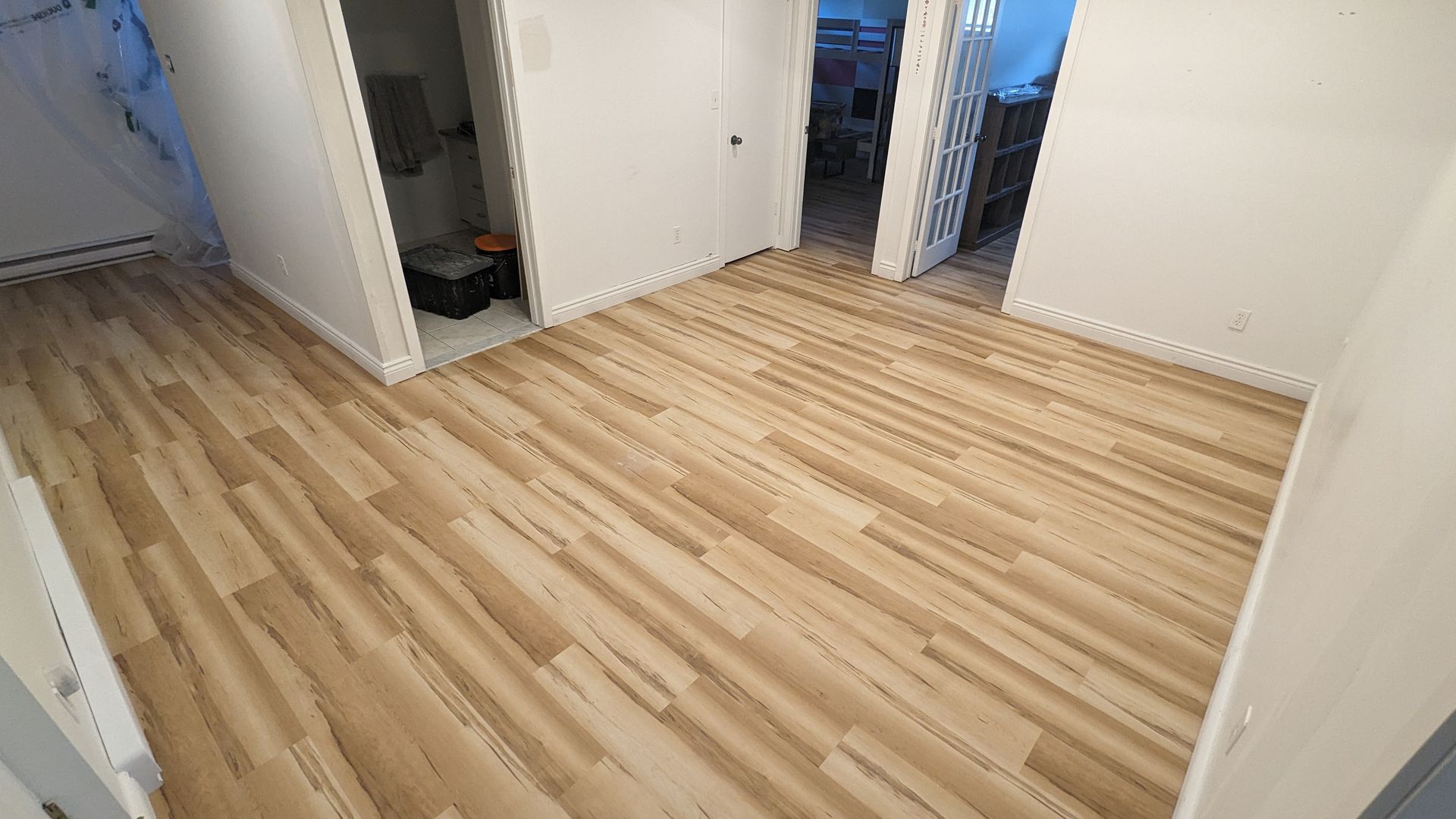 Une pièce avec un plancher en bois et des murs blancs.