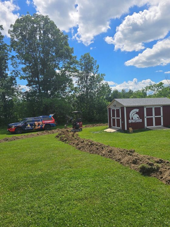 Red barn beside a grassy field and blue tractor under a bright blue sky with clouds
