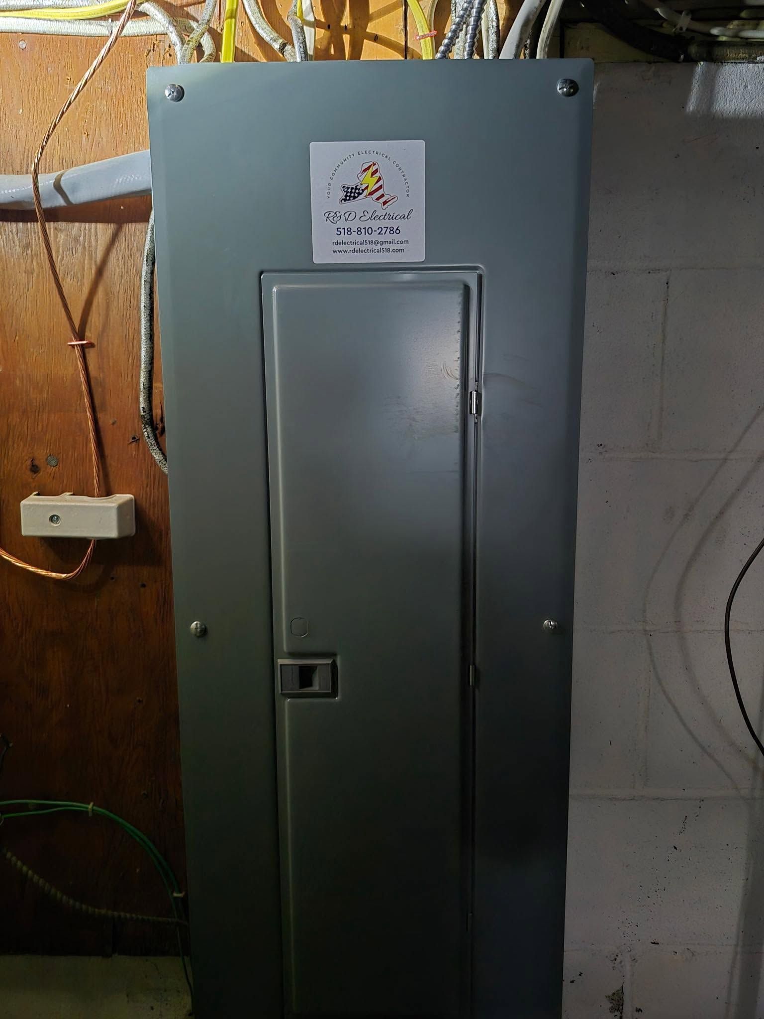 Gray electrical panel cabinet mounted on a concrete wall in a utility room