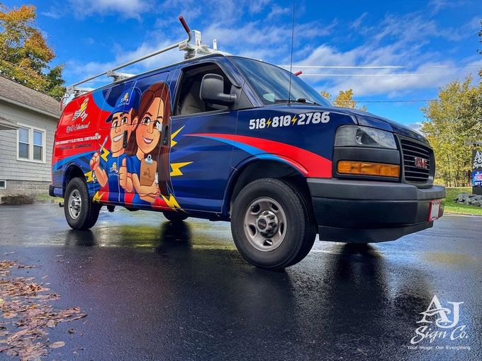 Blue-and-red service van with cartoon graphics parked on a wet driveway under a cloudy sky