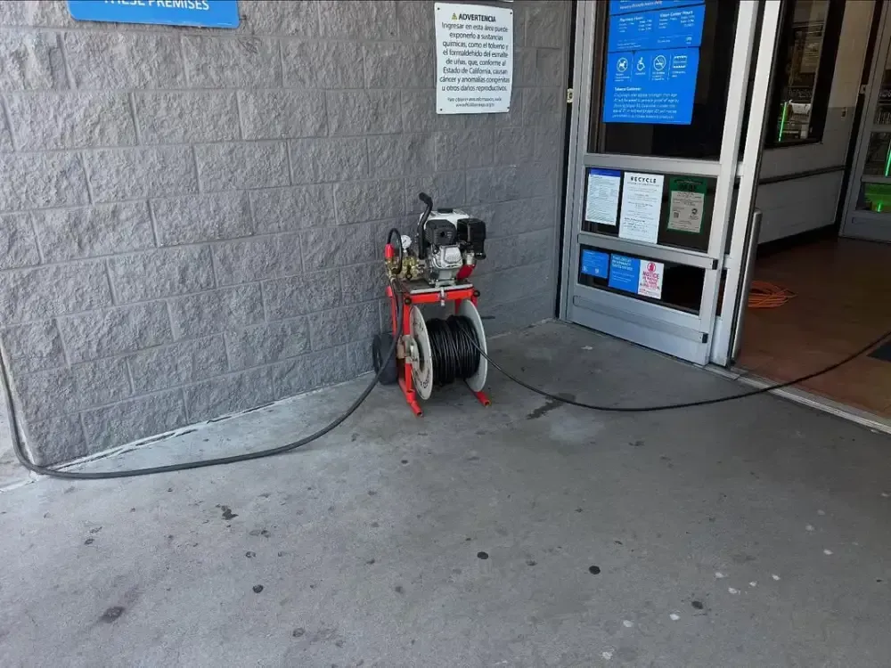 Small red mobility scooter parked beside a storefront entrance on a concrete sidewalk.