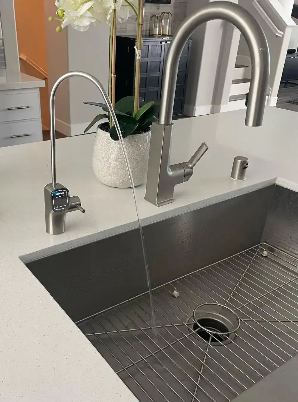 Modern kitchen sink with chrome faucet, soap dispenser, and potted plant on the counter