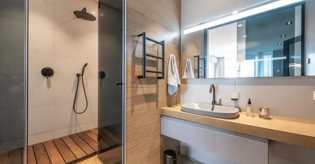 Modern bathroom with walk-in shower, wooden vanity, and large mirror with LED lighting.