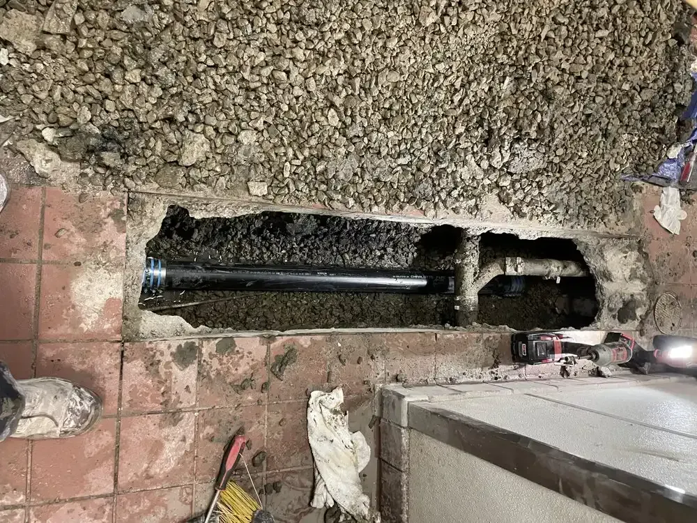 Excavated underground pipe or cable trench beside a sidewalk and building edge during repair work