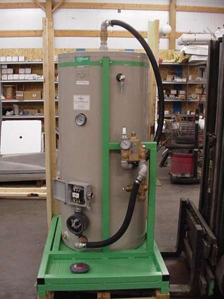 Large beige industrial machine on a green cart with black hose in a workshop aisle
