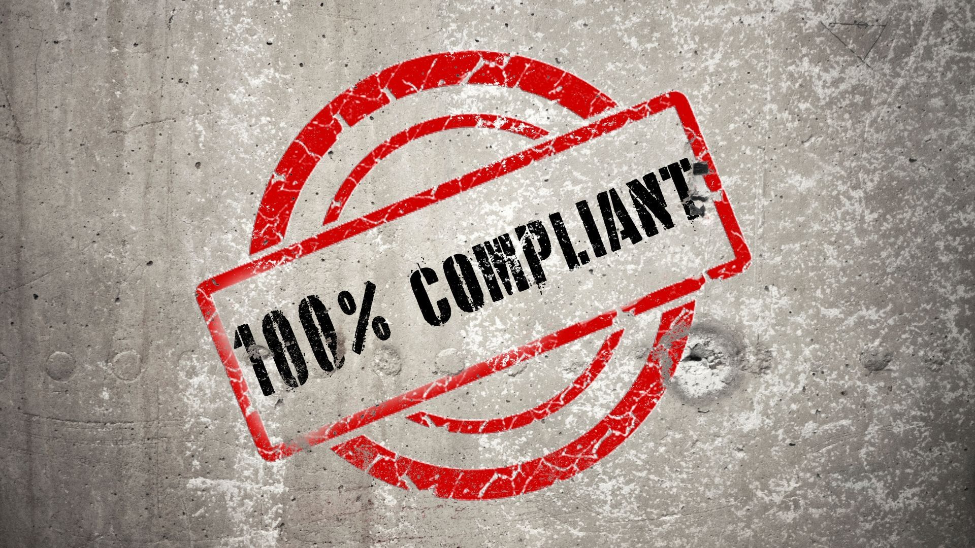Red “100% COMPLIANT” stamp over a weathered gray concrete background