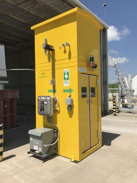Yellow industrial utility cabinet with mounted equipment on a concrete platform outdoors.