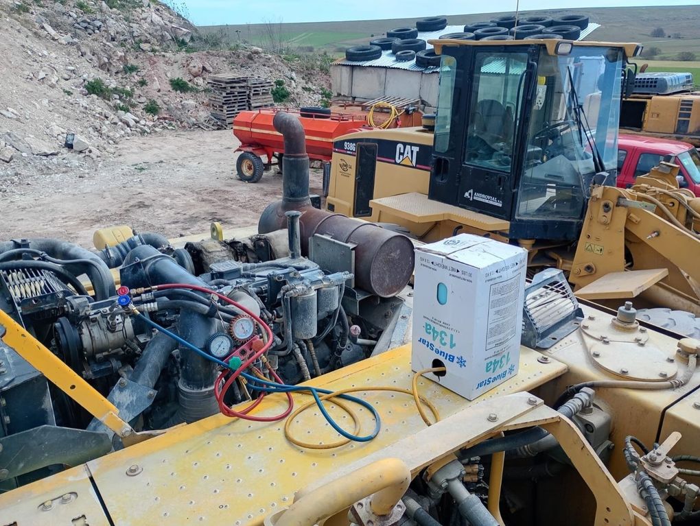 Maquinaria de construcción amarilla con partes del motor expuestas en una obra rocosa