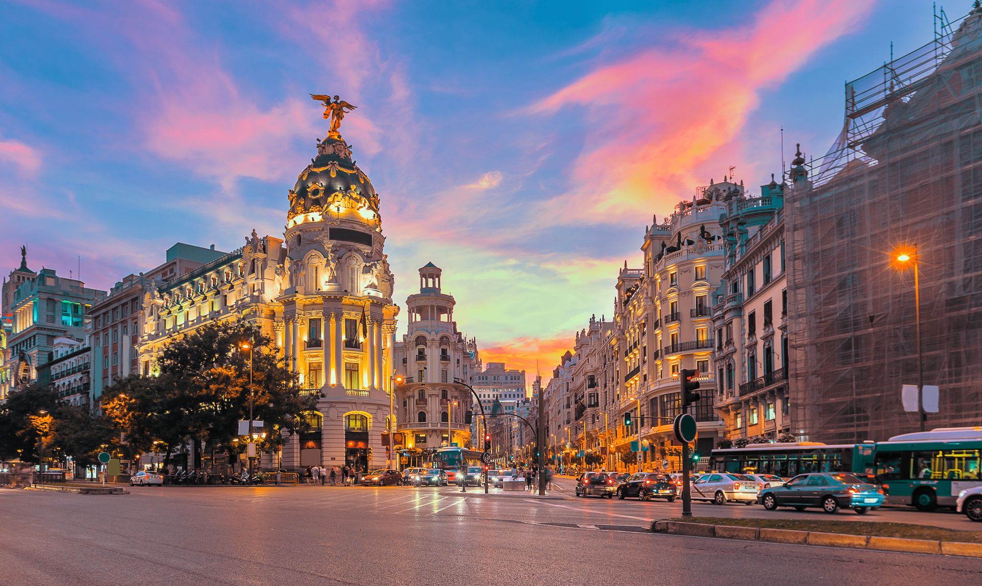 Sunset over a grand domed building and city street.