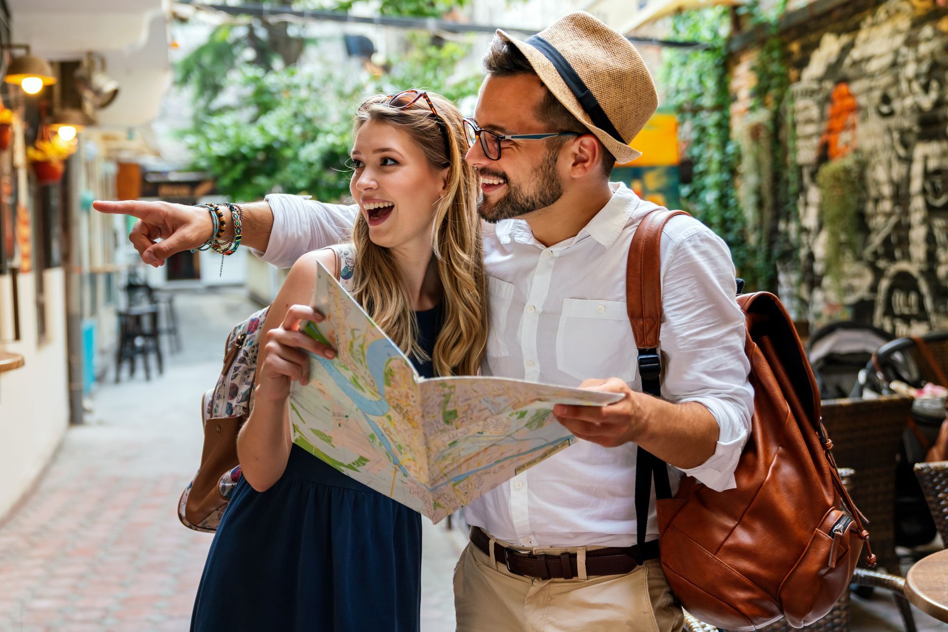Two tourists smiling and consulting a map on a narrow street.
