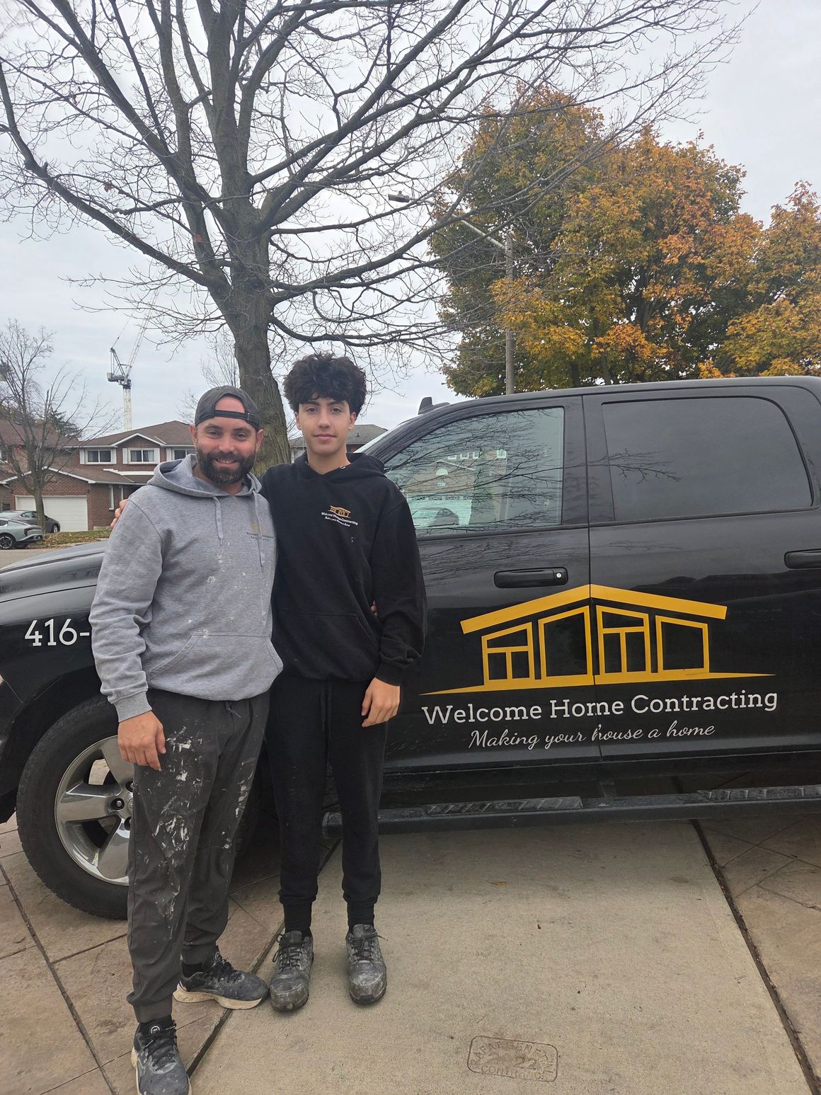 Two people standing beside a black service van with a yellow logo on a sidewalk