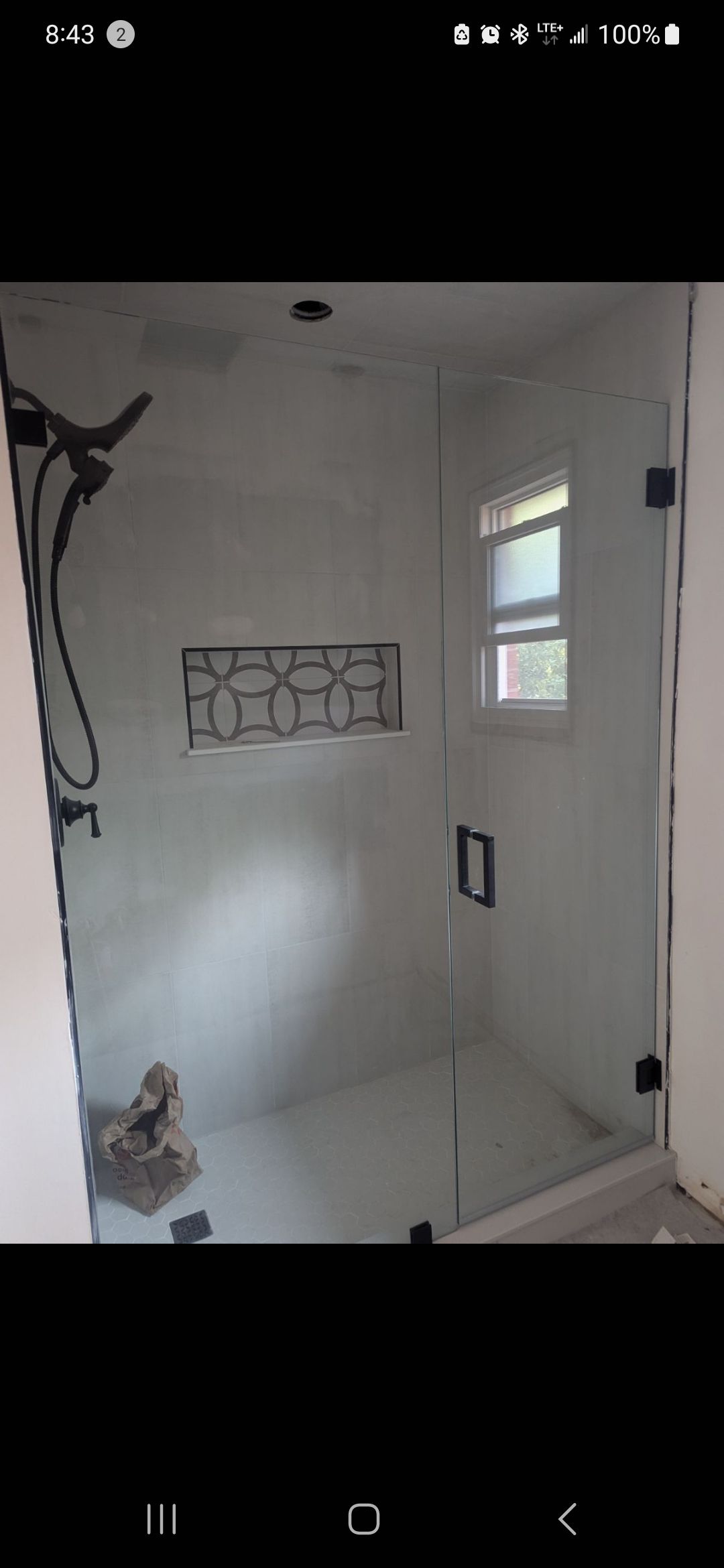 Glass shower enclosure with dark fixtures, built into a white-walled bathroom.