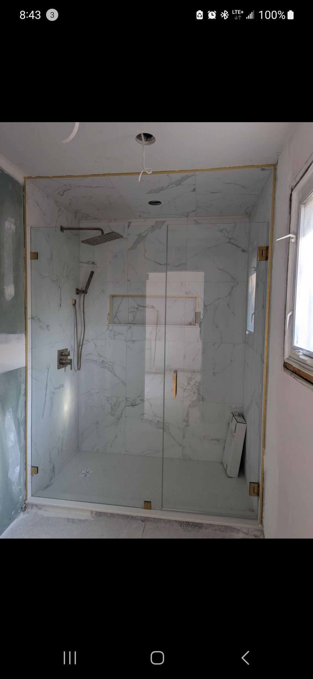 Glass shower enclosure with marble tile walls.